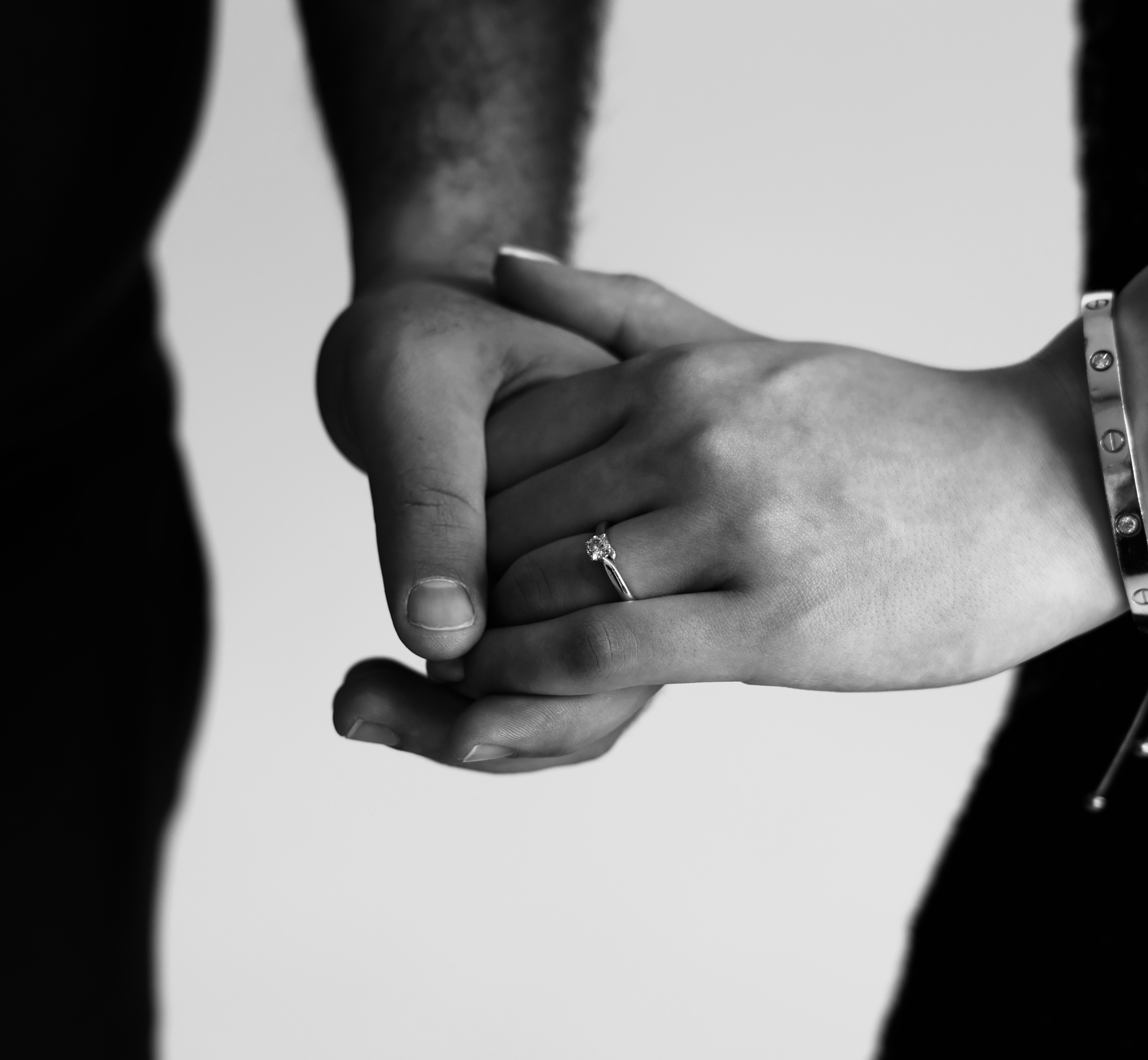 Black and white photograph of two hands clasped with a ring