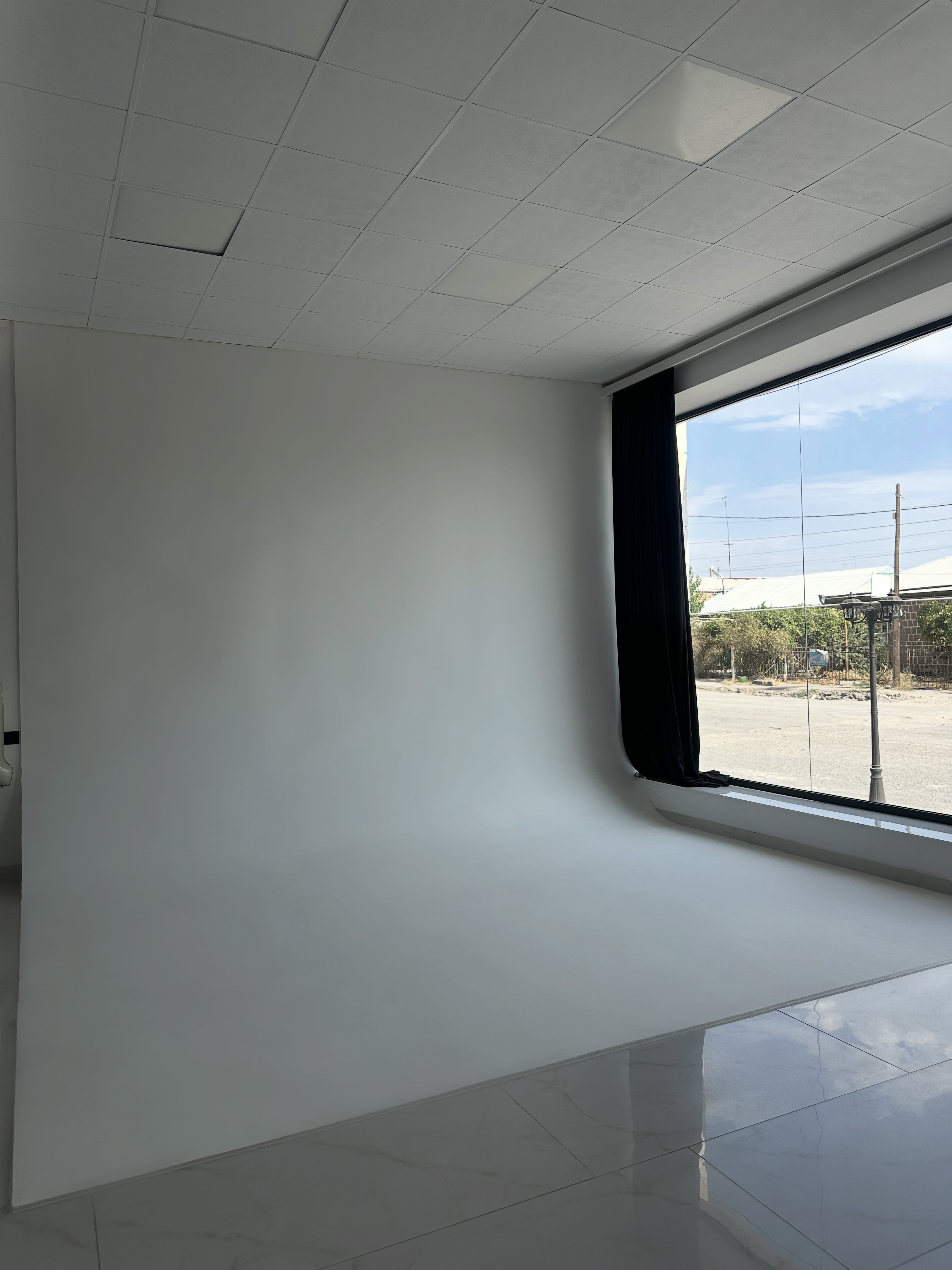 White cyclorama studio corner with a curved seamless wall and a large window looking onto the street